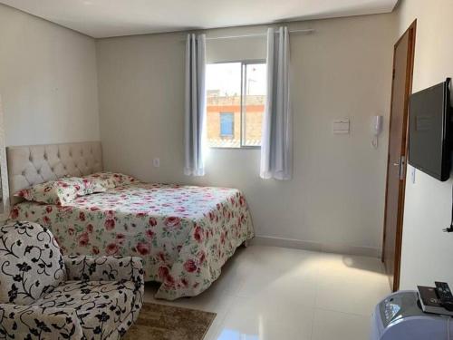 a bedroom with a bed and a chair and a window at kitnet208 No centro,c linda vista , tv smart e ar in Montes Claros