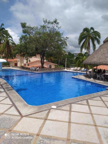 a large blue swimming pool with a thatch roof at Villas del Palmar Manzanillo with Beach Club in Manzanillo