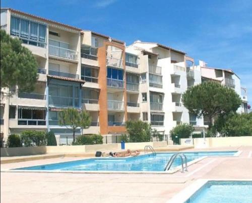 une piscine devant un grand immeuble d'appartements dans l'établissement Harmony - Résidence Nauticap plage RICHELIEU, au Cap d'Agde