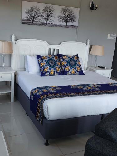 a bedroom with a large white bed with blue pillows at Fairway Guest Lodge in Margate