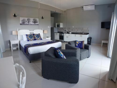 a bedroom with a bed and two couches and a kitchen at Fairway Guest Lodge in Margate