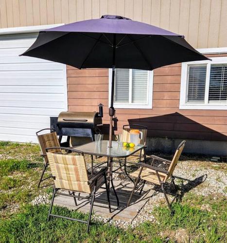 a table and chairs under an umbrella next to a grill at Private Cabin- Breakfast - Double Tub - 75in TV - SUP - Washer Dryer - BBQ in West Point