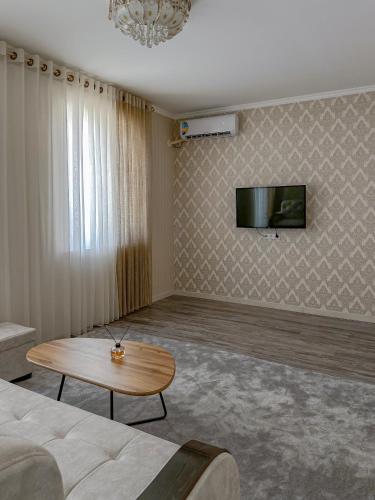 a living room with a couch and a table and a tv at Oasis Residence Fergana in Fergana
