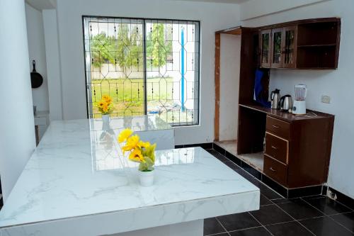 a kitchen with yellow flowers in a vase on a counter at Comfy home Mbezi beach - Nana Room in Dar es Salaam