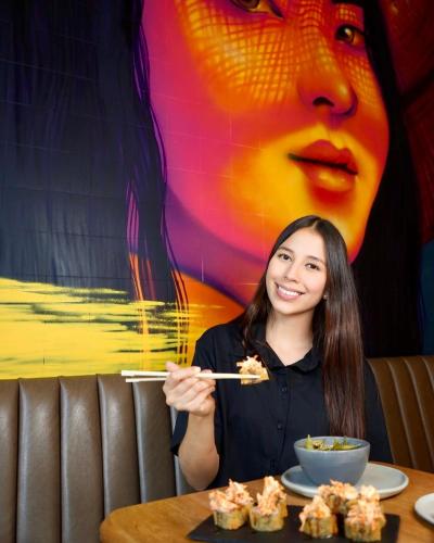 a woman sitting at a table eating food with chopsticks at Hotel Living by Armoniko in Medellín