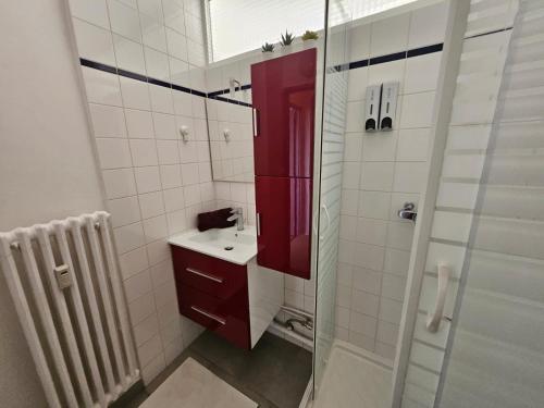 La salle de bains est pourvue d'une armoire rouge et d'un lavabo. dans l'établissement Studio La Belle Vue, à Metz
