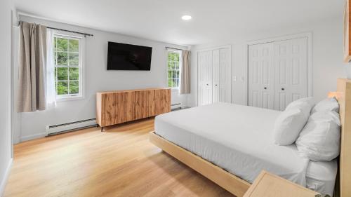 a white bedroom with a bed and a television at Aspen at Manchester in Manchester