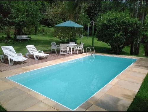a pool with chairs and a table and an umbrella at Quinta da Pedra do Elefante in Petrópolis