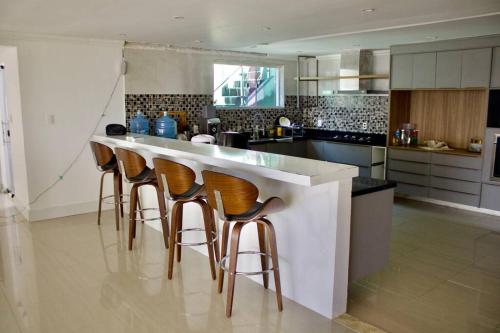 a kitchen with a bar with four stools at Mansão da Montanha in Niterói