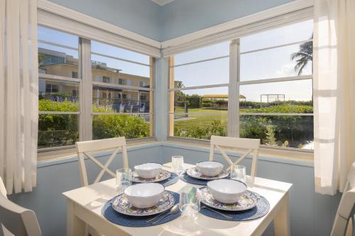 a dining room with a table and chairs and windows at Delray Breakers on the Ocean in Delray Beach
