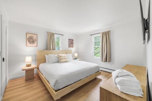 a white bedroom with a bed and two windows at Aspen at Manchester in Manchester