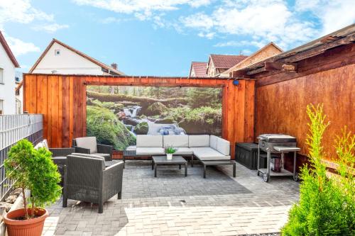 a patio with a white couch and a grill at Garten - Bergblick - Am Wasser - Parken - Harzquelle in Thale