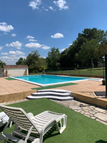 une piscine avec un fauteuil blanc et une piscine dans l'établissement Walnut and Chestnut Gites, à Mauzens-et-Miremont