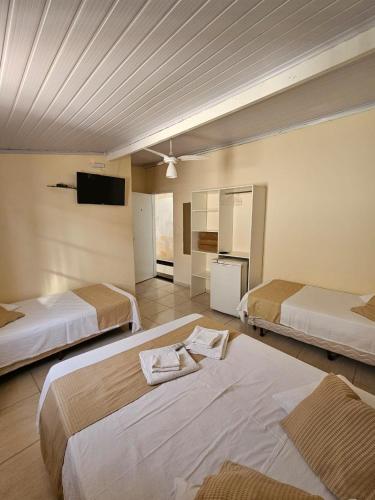 a hotel room with two beds and a flat screen tv at Pousada das Letras in São Thomé das Letras