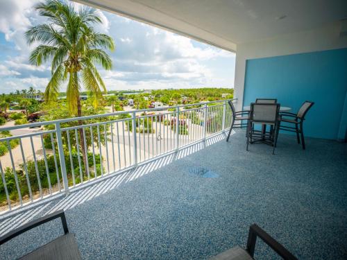 a balcony with a table and chairs and a palm tree at Sugarloaf Key Hotel at KOA Resort in Summerland Key