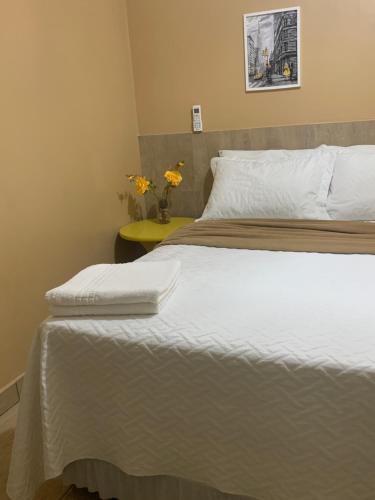 a bedroom with a bed and a yellow table at Hotel Coqueiros in Valparaíso de Goiás
