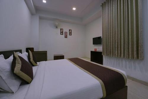 Un dormitorio con una gran cama blanca en una habitación. en Hotel Anugraha, en Kalyānpur