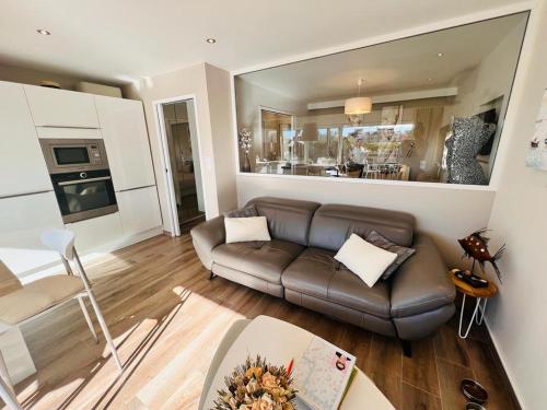 un salon avec un canapé marron et une cuisine dans l'établissement Village naturiste - La villa nature -, au Cap d'Agde