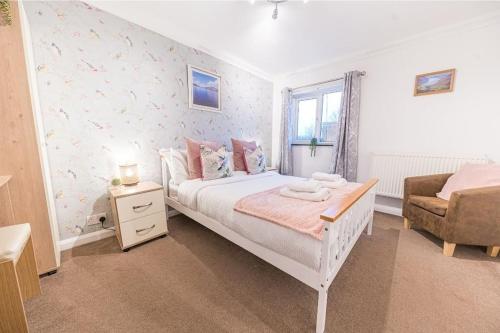 a bedroom with a white bed and a chair at 4 BR Holiday Home Steps from Keswick Town Centre in Keswick