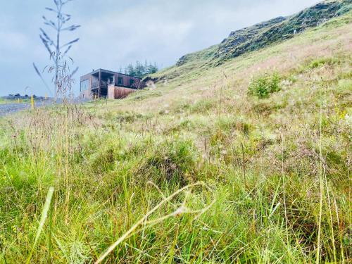 a house on the side of a hill with tall grass at Beautiful cottage with Mountain View in Fludir