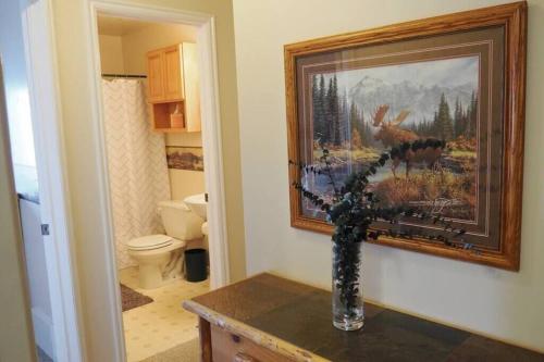 une salle de bain avec un tableau au mur et un vase avec des fleurs dans l'établissement Wild Moose Ski Lodge, à Eden