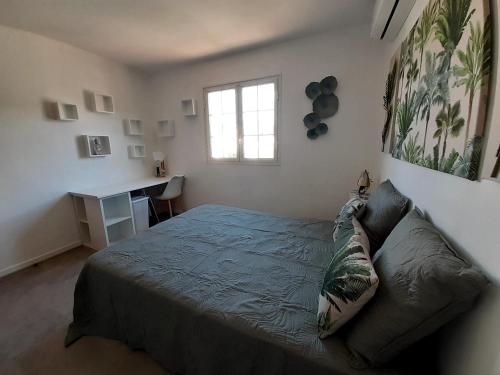 a bedroom with a bed and a desk and a window at Joli appartement, piscine, jacuzzi in Sainte-Suzanne