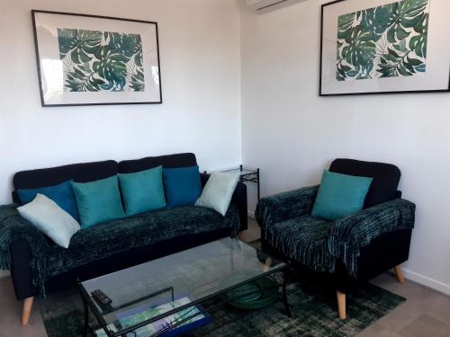 a living room with a couch and a glass table at Joli appartement, piscine, jacuzzi in Sainte-Suzanne