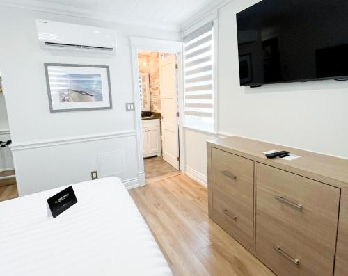 a living room with a tv on a white wall at Colonial Hotel & Suites in Grand Bend