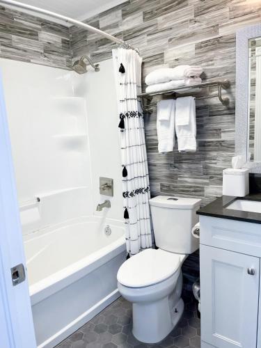 a bathroom with a white toilet and a bath tub at Colonial Hotel & Suites in Grand Bend