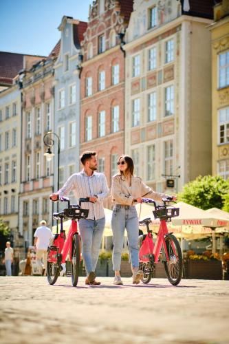 a man and a woman standing next to two bikes at Boutique Residence Gdańsk in Gdańsk