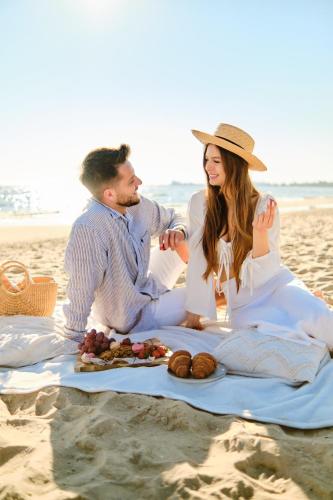 a man and a woman sitting on a blanket on the beach at Boutique Residence Gdańsk in Gdańsk