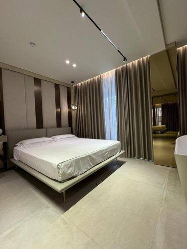 a bedroom with a large white bed in front of a window at Hotel Miramare in Vlorë