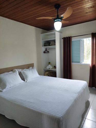 a bedroom with a white bed with a ceiling fan at Pousada Vegas in São Roque