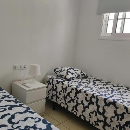 a bedroom with two beds and a lamp on a night stand at My Little Bungalow in Palm-Mar