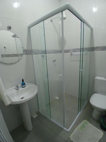 a bathroom with a glass shower and a sink at Hospedagem Famíliar in Cotia