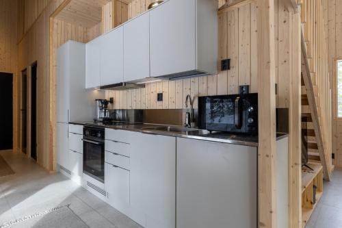 a kitchen with white cabinets and a microwave at Villa Kuusi by HiYlläs in Äkäslompolo