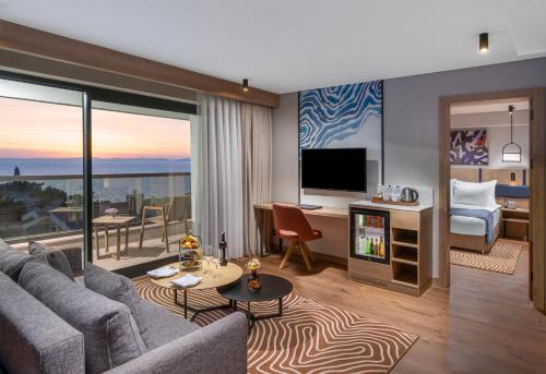 a living room with a couch and a television and a bed at Elite World Kuşadası in Kusadası