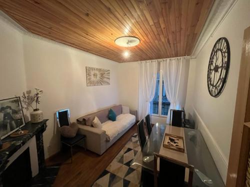 un salon avec un canapé et une horloge au mur dans l'établissement Aux portes de Paris, à Clichy