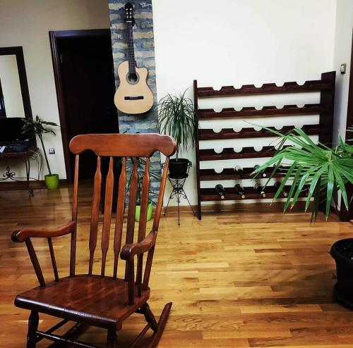 a wooden rocking chair in a living room with a guitar at Villa Royal in Belgrade