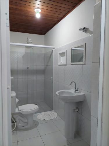 a white bathroom with a toilet and a sink at Pousada Vegas in São Roque