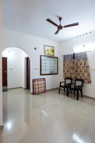 a living room with two chairs and a ceiling fan at Nest Villa - A Homely Heaven Near the Skies in Nedumbassery