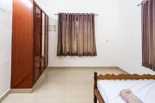 a bedroom with white walls and a bed and curtains at Nest Villa - A Homely Heaven Near the Skies in Nedumbassery