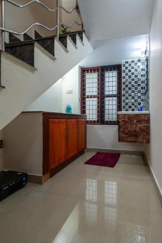 a living room with a staircase and a kitchen at Nest Villa - A Homely Heaven Near the Skies in Nedumbassery