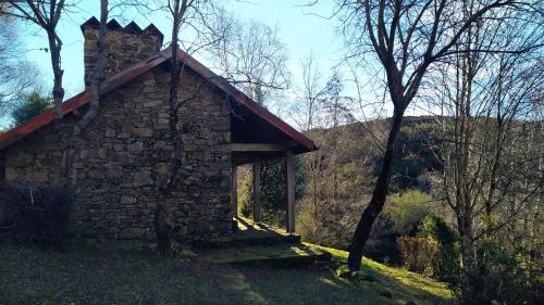an old stone building with a chimney and trees at Aveleira EcoCasa in Melgaço