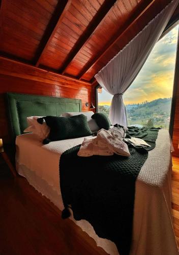 a bedroom with a bed and a window with a view at Capanna del Vale - Refúgio & Degustação no Vale dos Vinhedos in Bento Gonçalves