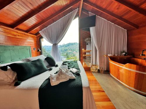 a bedroom with a large bed and a large window at Capanna del Vale - Refúgio & Degustação no Vale dos Vinhedos in Bento Gonçalves
