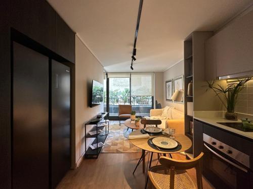 a kitchen and living room with a table in a room at HOM I Lujoso Depto 2D2B, Ñuñoa con Estacionamiento in Santiago