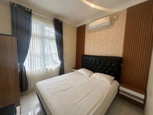 a bedroom with a bed with a black headboard and a window at Eton Asia Villas-Kota Bunga in Puncak