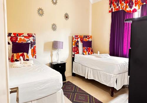 two beds in a room with purple curtains at Jamnick Vacation Rentals - Fern Court, Richmond Estate, St Ann, Jamaica in Ocho Rios