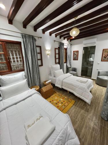 a bedroom with two beds and a living room with a couch at Riad Safia in Rabat
